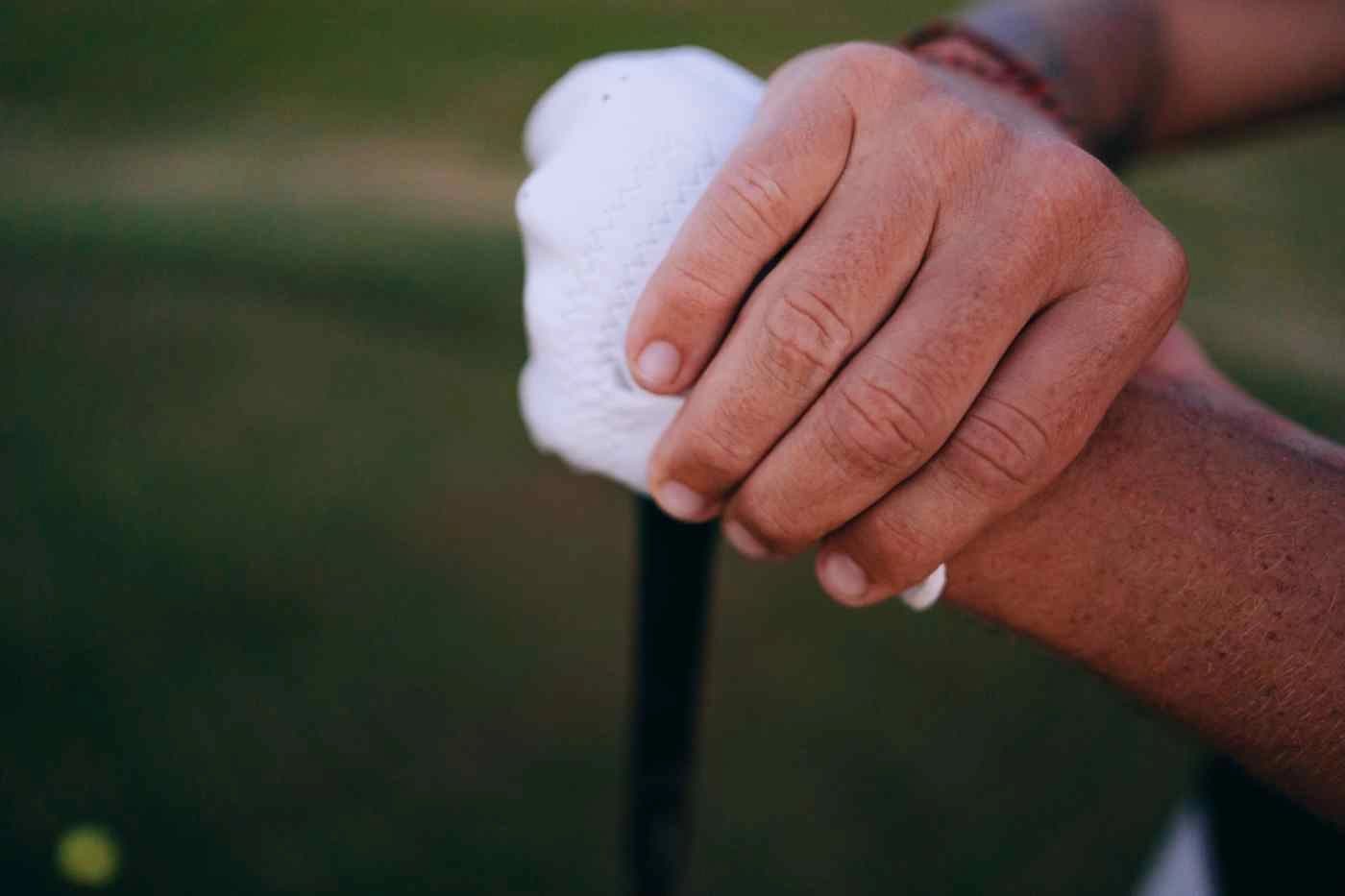 Hands gripping a golf club on a putting green